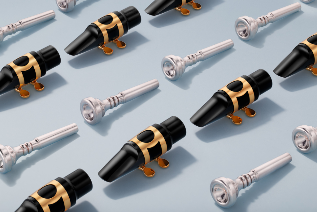 Many trumpet and saxophone mouthpieces lying on surface